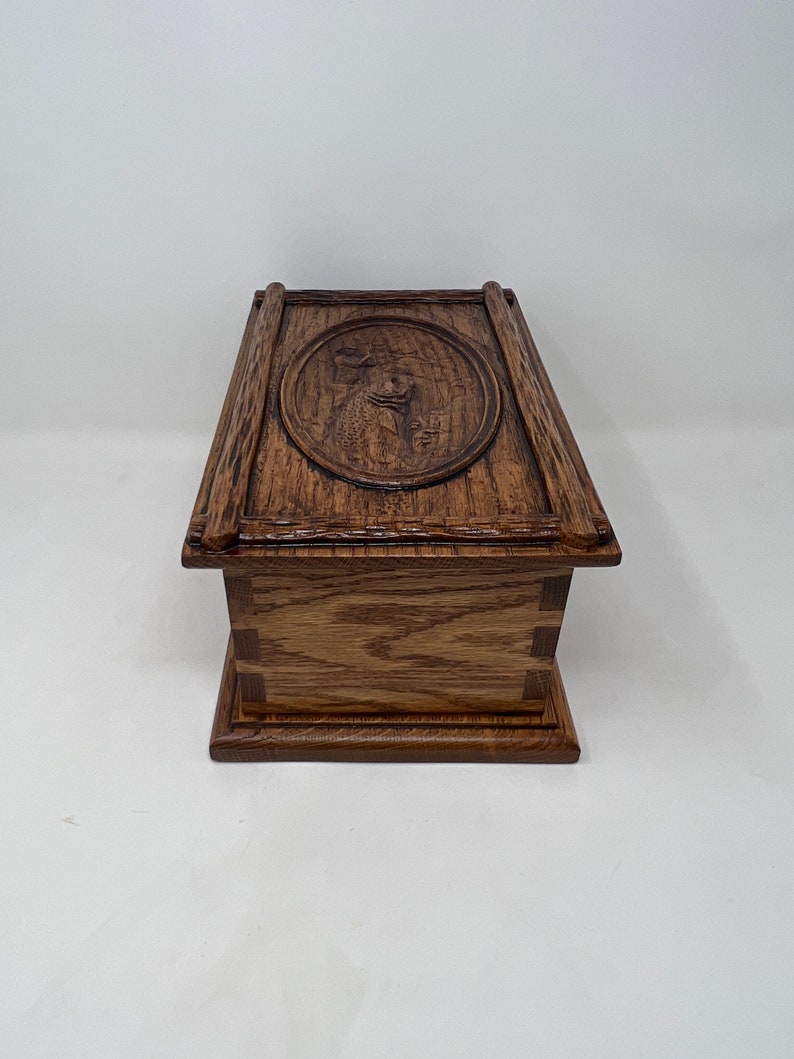 May include: A wooden box with a carved design on the lid. The box is made of oak wood and has a dark brown finish.