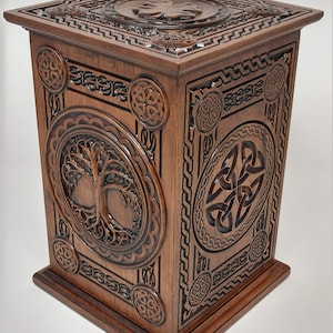 May include: A wooden box with intricate Celtic knotwork carvings. The box features a tree of life design on one side and a shamrock on the top.