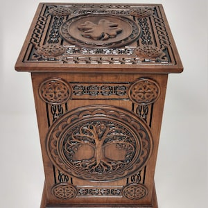 May include: A wooden box with intricate carvings of Celtic knots and a tree of life design. The top of the box features a carved shamrock.