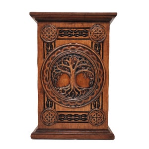May include: A wooden box with a Celtic knot design and a carved tree of life on the front. The box is brown and has a rectangular shape.