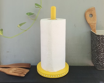 May include: Yellow paper towel holder with a white paper towel roll. The holder has a white polka dot design around the base.
