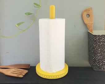 May include: Yellow paper towel holder with a white paper towel roll. The holder has a yellow base with white polka dots.