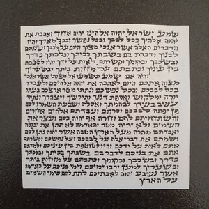 May include: A black and white image of a Hebrew text on a white paper background. The text is written in a traditional Hebrew script and includes the words "Shema Yisrael" and "Adonai Eloheinu Adonai Echad".