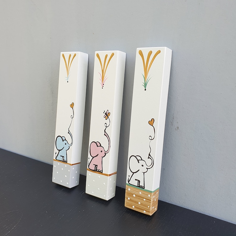 Hand painted elephant mezuzah case on white wood available in natural wood, blue or pink elephant design with gold accents. Personalized Jewish nursery decor for baby room, kids room mezuzah and meaningful newborn gift with custom name.