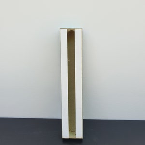 May include: A brown cardboard box with a white interior and a slot cut out of the front. The box is standing on a black surface.