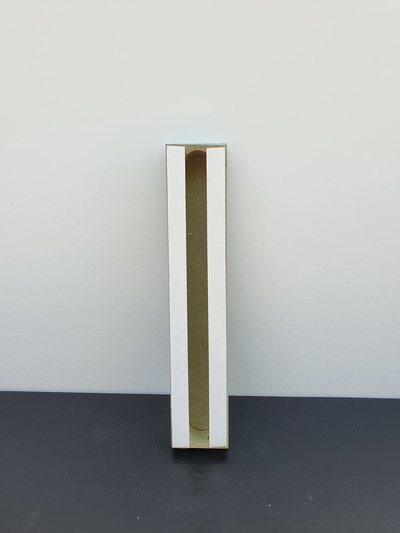 May include: A brown cardboard box with a white interior and a slot cut out of the front. The box is standing on a black surface.