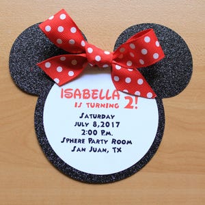 May include: A Minnie Mouse-shaped birthday invitation with a red and white polka dot bow. The invitation includes the text "ISABELLA IS TURNING 2!" and event details: Saturday, July 8, 2017, 2:00 P.M., Sphere Party Room, San Juan, TX.