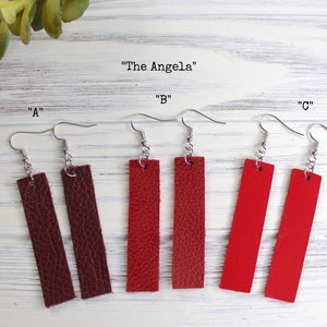 May include: Three pairs of rectangular dangle earrings in shades of brown, red, and bright red. Each pair has a silver-tone hook. The text "The Angela" and letters "A", "B", and "C" are above the earrings.
