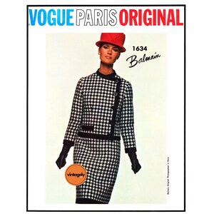 May include: A black and white houndstooth patterned suit with a red hat. The suit includes a jacket and skirt. The text "Vogue Paris Original" is at the top of the image. The text "1634 Balmain" is in the upper right corner of the image.