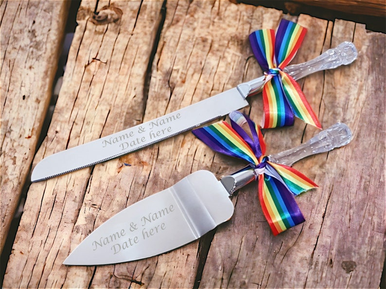 May include: A set of two silver cake knives with clear handles and rainbow ribbon bows. The knives are engraved with "Name & Name Date here".