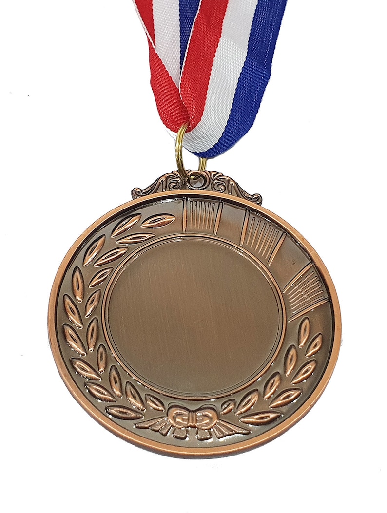 Peut inclure: Une m&eacute;daille de bronze avec un design de couronne de laurier et un ruban attach&eacute;. La m&eacute;daille a un espace vide au centre pour la gravure.