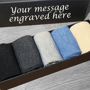 May include: A black gift box with the text "Your message engraved here" on the lid. The box contains six pairs of socks in various colours, including black, grey, blue, and beige.