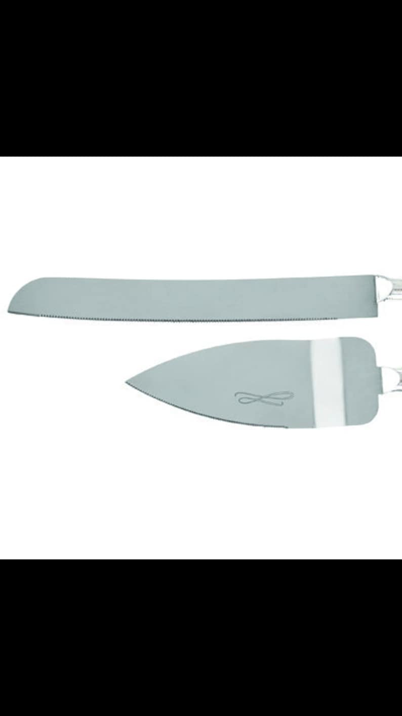 May include: A silver cake knife set with a serrated blade and a smooth, rounded spatula. The spatula has a decorative design.