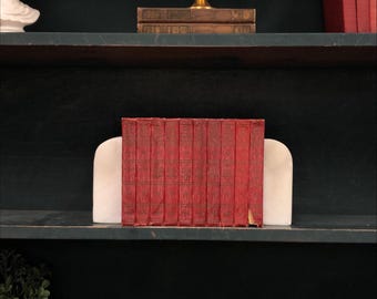 Juego de 10 libros clásicos de tapa dura: volúmenes rojos ornamentados para exhibición.