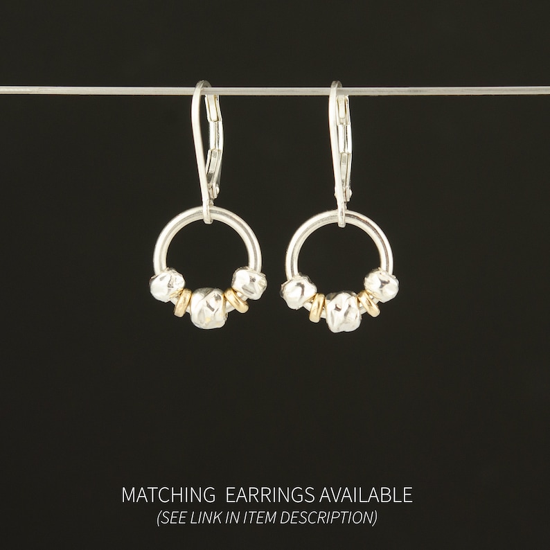 Puede incluir: Un par de pendientes con cierre de palanca y dise&ntilde;o de aro circular. Cada aro est&aacute; adornado con tres peque&ntilde;as cuentas plateadas texturizadas y dos cuentas espaciadoras doradas lisas. El texto inferior dice: MATCHING EARRINGS AVAILABLE (SEE LINK IN ITEM DESCRIPTION).