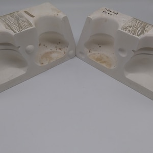 May include: Two white ceramic molds with a textured surface. The molds are shaped like a half-sphere and have a small hole in the center. The text "5415A" and "1771" is written on the mold.