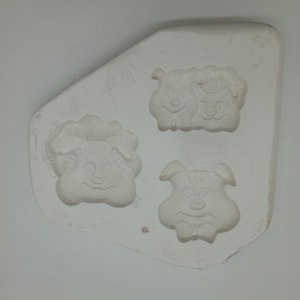 Peut inclure: Moule en céramique blanche avec trois motifs de cochons. Le moule porte l'inscription "Sugar".