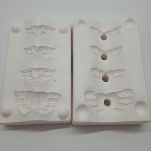 May include: Two white ceramic moulds with four detailed butterfly designs on each side. The moulds are designed for creating resin or polymer clay jewellery.