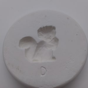 Peut inclure: Moule en céramique blanche avec un motif en relief d'un écureuil. Le moule a une lettre "D" au fond.