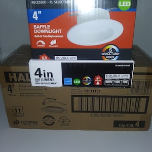 May include: A brown cardboard box with a white and red HALO 4-inch recessed downlight. The box has a white LED light bulb, a white trim, and a white baffle. The box also has a white label with the text "5 seleCCTable colors" and "Double Life". The box is labeled with the product number 13511151 and the quantity 4.