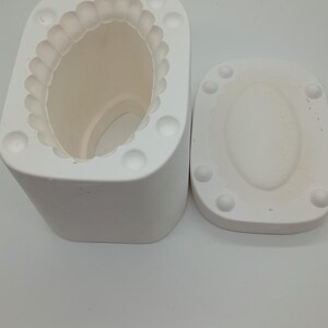 May include: White ceramic mould with a scalloped edge and a round opening. The mould is designed for making candles or soap. It comes with a separate lid.