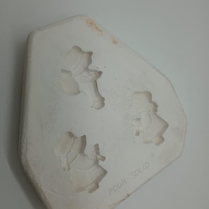 Peut inclure: Moule en céramique blanche avec trois empreintes d'enfants en robe. Le moule porte l'inscription "Pour Solid" au fond.