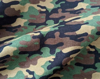 Puede incluir: Tela de camuflaje con un patrón verde, marrón y negro. La tela está doblada por la mitad, mostrando el patrón en ambos lados.