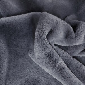 May include: Close-up of a soft, gray faux fur fabric. The fabric is folded and draped, showing the texture and pile of the material.