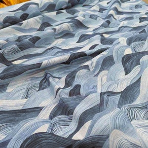May include: A close-up of a fabric with a flowing, wave-like pattern in shades of blue and white. The design resembles a stylized landscape of rolling hills or ocean waves, creating a textured and dynamic visual effect. The fabric appears to be soft and pliable.