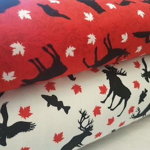 May include: Two pieces of fabric with a repeating pattern of black moose, deer, birds, and maple leaves. The top fabric is red with white maple leaves and the bottom fabric is white with red maple leaves.