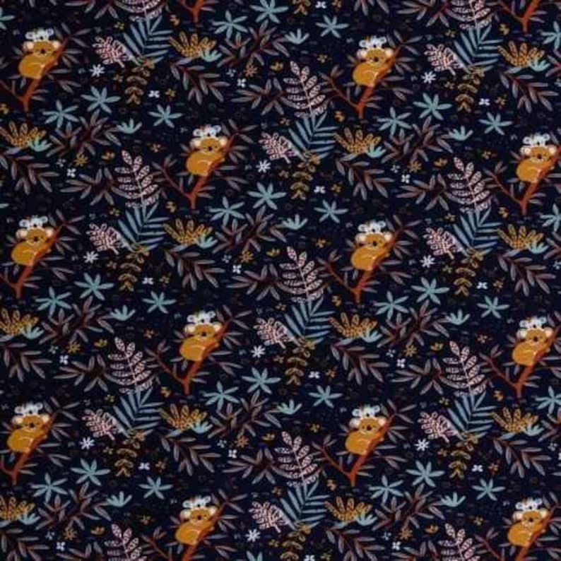 May include: A dark blue fabric with a repeating pattern of koalas sitting in trees. The trees are stylized and have brown branches and green leaves. The koalas are brown with white ears and noses. The background is a dark blue with small white stars and other floral details.