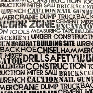 May include: A white fabric background with black text printed on it. The text includes words related to construction, such as "work zone", "excavator", "bulldozer", "cement", "miter saw", "bricks", "hardhat", "building site", "backhoe", "chisel", "hammer", "drill", "safety", "wrench", "caution", "nail gun", "dump truck", "crane", and "tools".