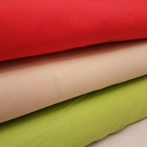 May include: Three fabric swatches in different colors: red, beige, and green. The fabric is a woven canvas material.