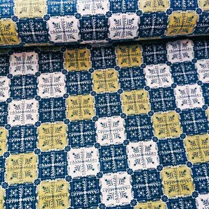 May include: A repeating pattern of blue, white and yellow squares with a geometric design. The pattern is reminiscent of a traditional quilt.