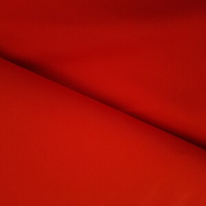 May include: A close-up of a red fabric with a smooth texture. The fabric is folded in half, creating a diagonal line.