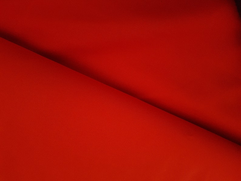 May include: A close-up of a red fabric with a smooth texture. The fabric is folded in half, creating a diagonal line.