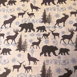 May include: A beige fabric with a repeating pattern of brown silhouettes of various animals, including bears, deer, moose, and wolves. The background features a light blue snowflake pattern.