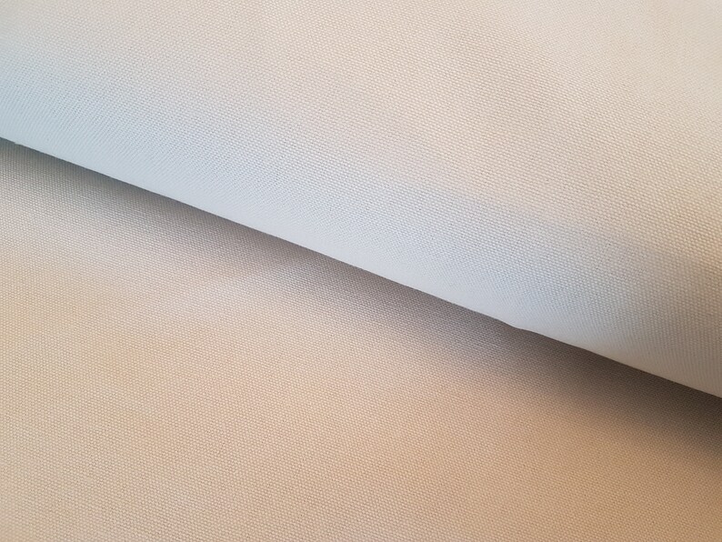 May include: Close-up of a light beige fabric with a subtle woven texture. The fabric is folded in half, showing the smooth surface on one side and the textured surface on the other.