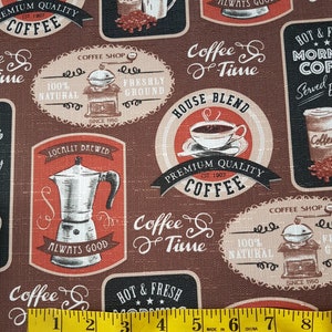 May include: A brown fabric with a repeating pattern of coffee-themed illustrations. The illustrations include coffee cups, coffee pots, coffee beans, and text that says "House Blend", "Premium Quality Coffee", "Coffee & Time", "Hot & Fresh Morning Coffee", "Served Everyday", "Coffee Shop", "Locally Brewed", "Always Good", and "100% Natural". A yellow measuring tape is placed across the bottom of the fabric.