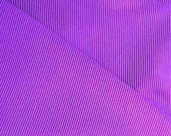 May include: Purple pleated fabric with a diagonal pattern. The fabric has a smooth, silky texture.