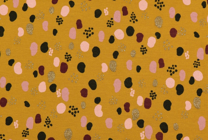 May include: Mustard yellow fabric with a repeating pattern of pink, black, and burgundy abstract shapes. The fabric has a subtle glitter finish.