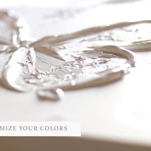Op de afbeelding: Close-up van een wit, getextureerd verfdesign op een canvas. De verf is dik en heeft een 3D-effect. De tekst "CUSTOMIZE YOUR COLORS" staat onderaan de afbeelding.