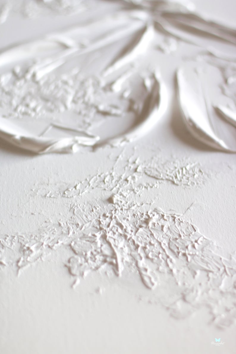 Op de afbeelding: Witte textuurverf op een canvas. De verf is aangebracht in dikke lagen, waardoor een driedimensionaal effect ontstaat.