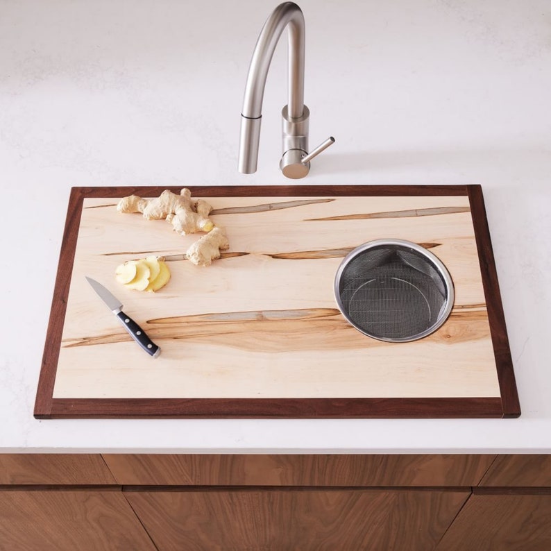 Cutting board with hole cutout that a metal mesh basket fits inside. this sink cover goes over sink and is made of ambrosia maple and  walnut.