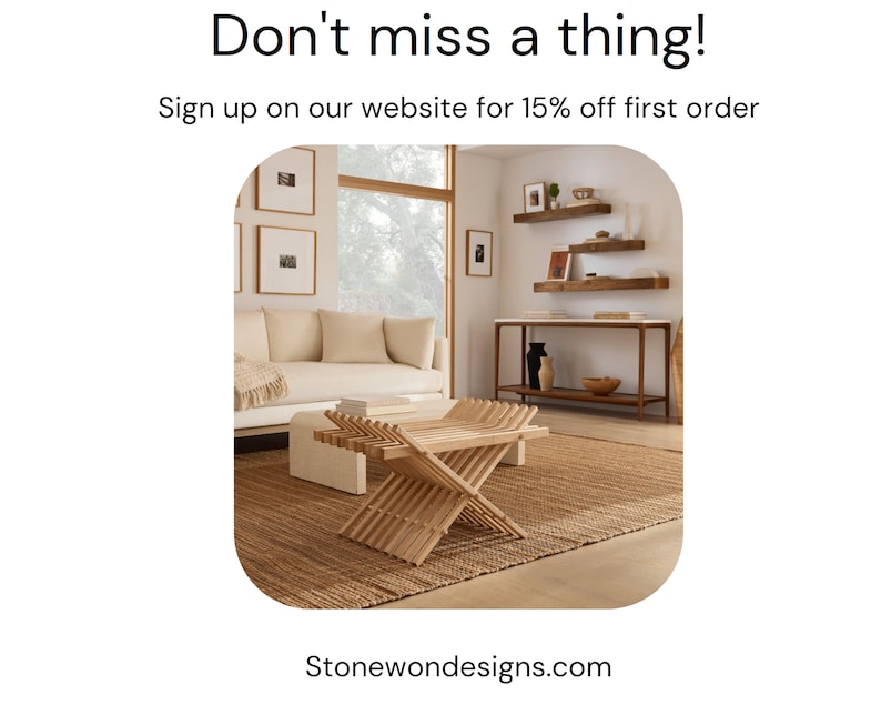 May include: A light brown wooden folding table with a woven rug underneath. The table is in a living room with a white couch and a wooden shelf unit with decorative items.