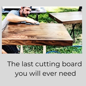 May include: A close-up of a large, wooden chopping board being finished with a sanding block. The board has a rich brown colour and a beautiful grain pattern. The board is sitting on a wooden stand.