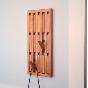 May include: A wooden wall-mounted coat rack with a geometric design. The rack has multiple hooks and is made of light brown wood.