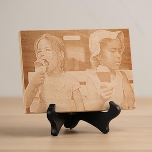 May include: A wooden plaque with a laser-engraved image of two children eating ice cream cones. The plaque is on a black stand.