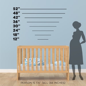 May include: A wooden crib with a blue and white patterned blanket inside. A silhouette of a person standing next to the crib is 66 inches tall, as indicated by the height markings on the wall behind the crib.