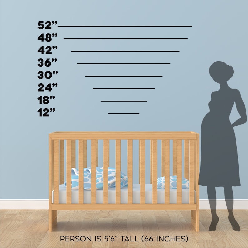 May include: A wooden crib with a blue and white patterned blanket inside. A silhouette of a person standing next to the crib is 66 inches tall, as indicated by the height markings on the wall behind the crib.